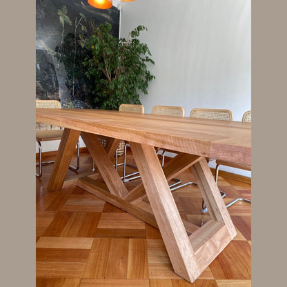 Detalle de la base de madera lenga de la mesa de comedor Italia sobre parquet