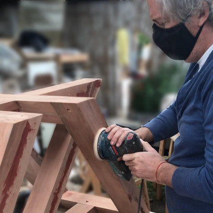 Carpintero lijando la base de madera de la mesa de comedor Italia
