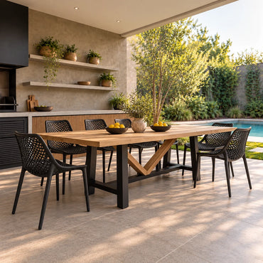 Mesa de terraza Viena en lenga natural con base de fierro negro y travesaño en V, con sillas negras caladas, junto a una piscina (imagen referencial)